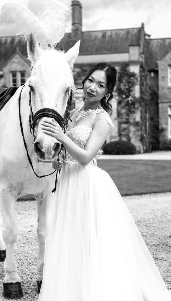 Bride wearing couture altered Riki Dalal wedding dress beside white horse at the venue