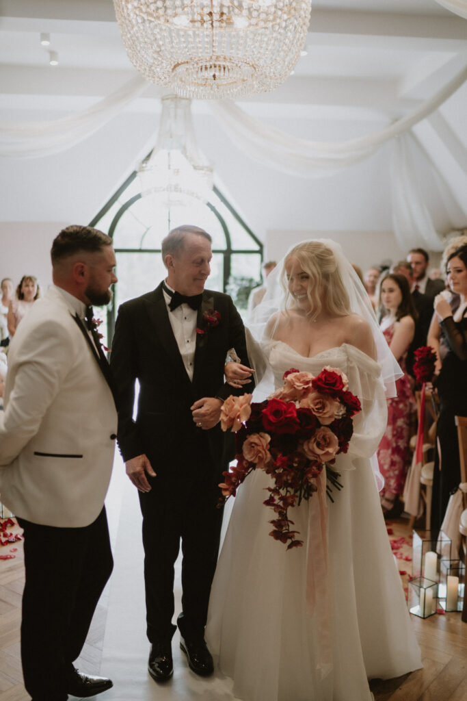 Bride wearing altered Essense of Australia gown during wedding ceremony walking with dad