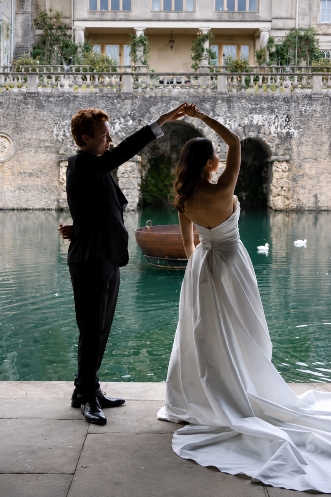 Bride dancing beside the water in a minimalist Morilee wedding dress after couture bridal alterations