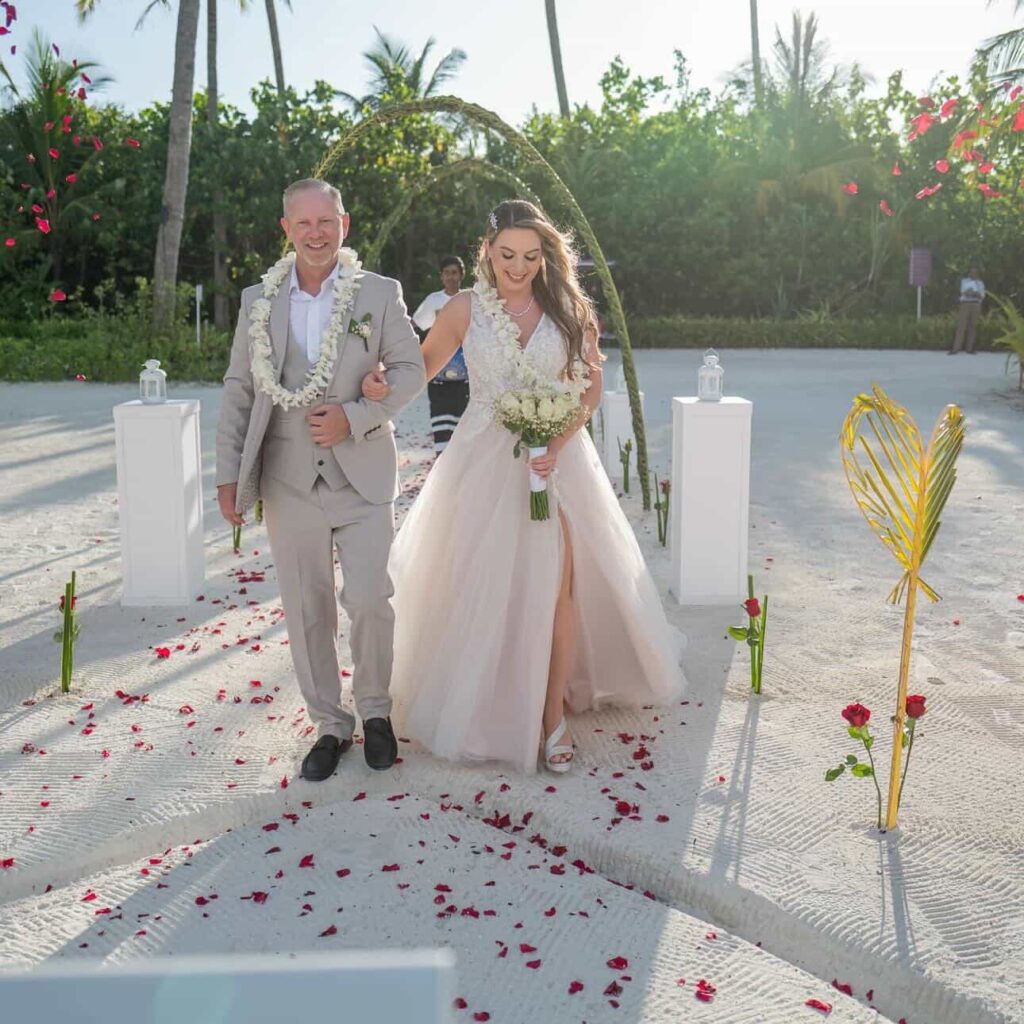 Bride and groom walking on Maldives beach in altered Stella York wedding dress