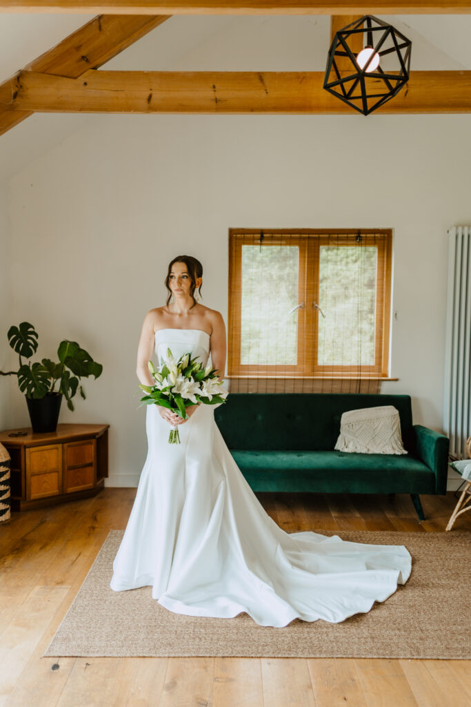 Bride and groom walking together showing fitted mikado wedding dress with bow back detail after bridal alterations Horsham
