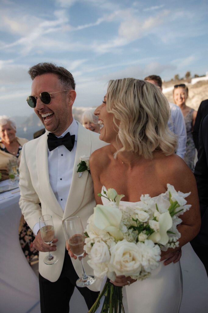 Bride and groom walking through the streets of Santorini with the bride wearing a beautifully fitted Khya wedding dress