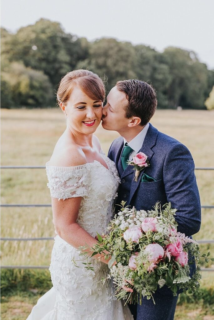 Bride wearing altered Anny Lin wedding dress during Surrey wedding outside kissing