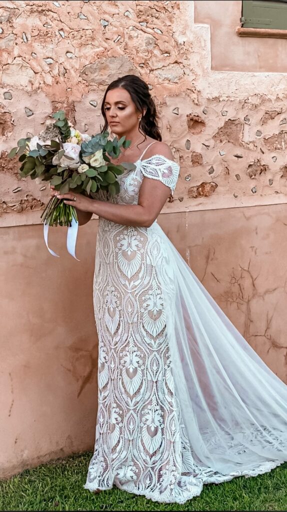 Bride wearing Madi Lane India wedding dress with bespoke Bardot sleeves, detachable waist cape and skin-tone lining