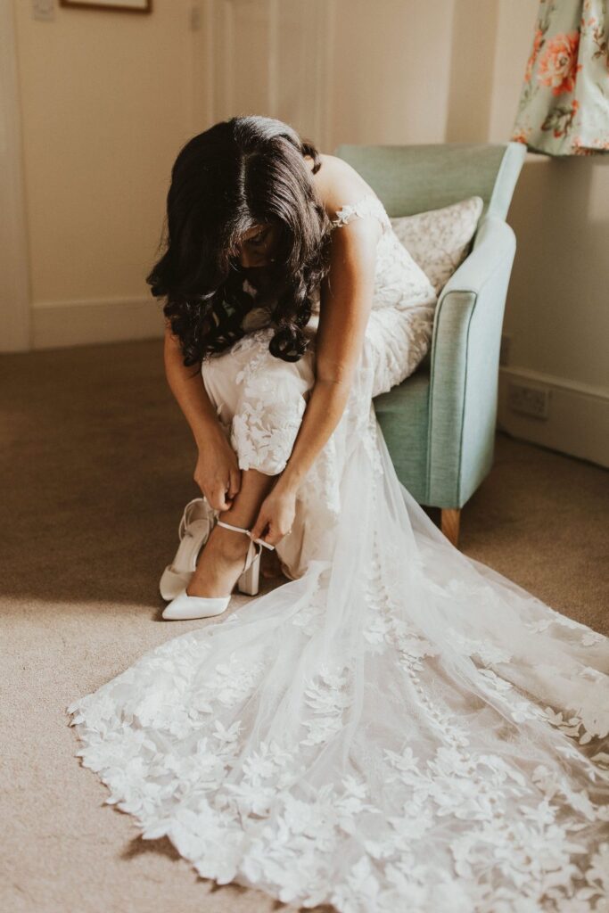 Allure Bridal alterations – bride getting ready in her perfectly fitted Allure Bridal wedding dress tieing shoes
