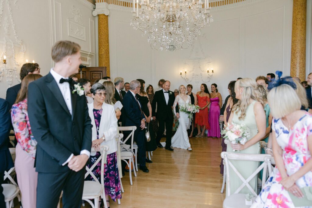  walking down the isle with father Elegant silhouette of a WED2B Fabien wedding dress after professional alterations