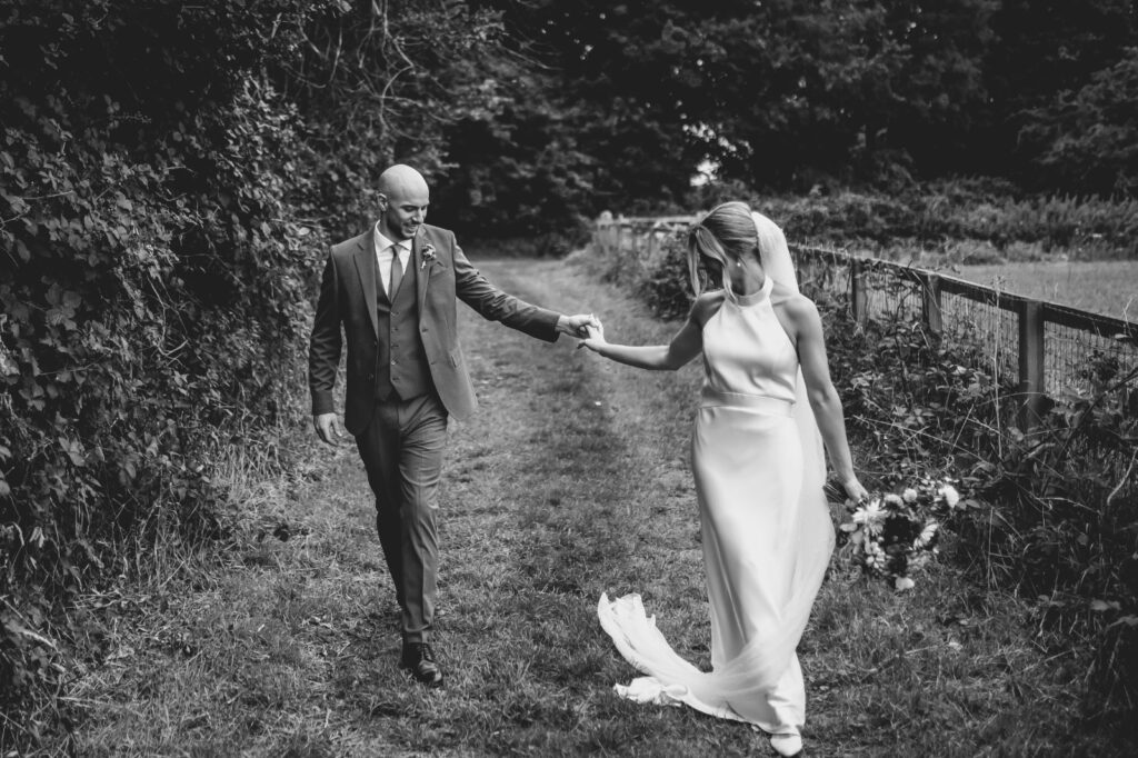 Redhill bride wearing a Catherine Deane Kin gown after couture bridal alterations, posing with her groom black & white