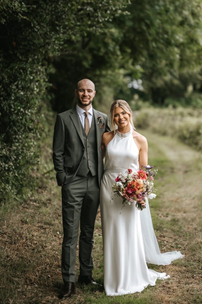 Redhill bride wearing a Catherine Deane Kin gown after couture bridal alterations, posing with her groom 