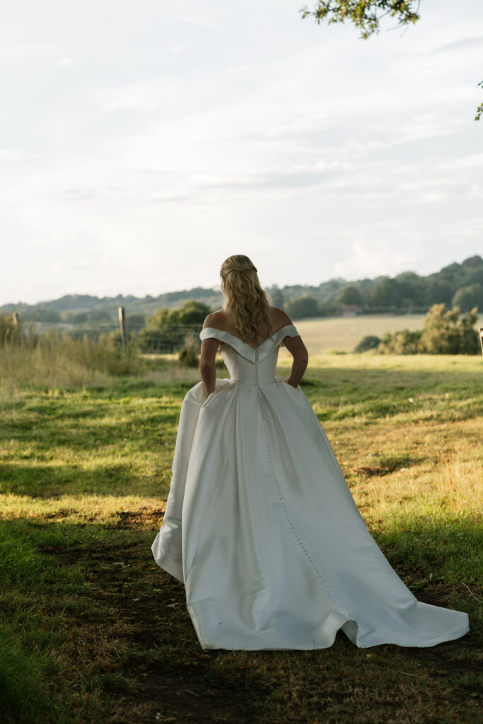 Bride walking in countryside back view of gown