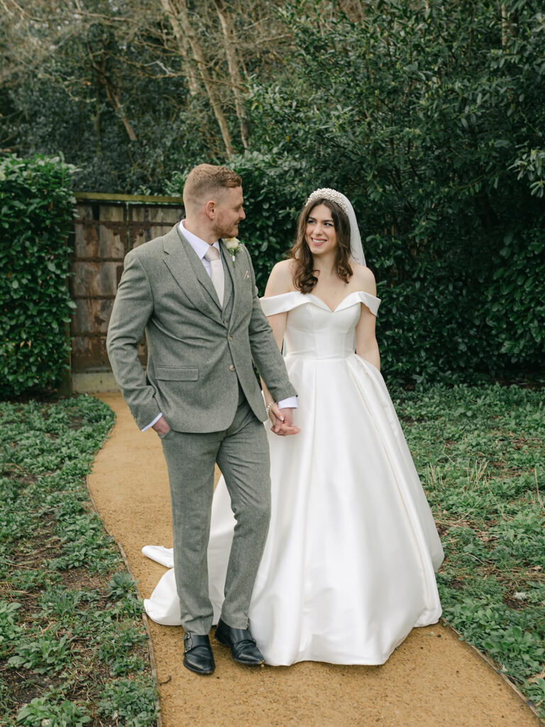 Bride wearing a Stella York wedding dress after expert bridal alterations, walking with her groom on their wedding day.