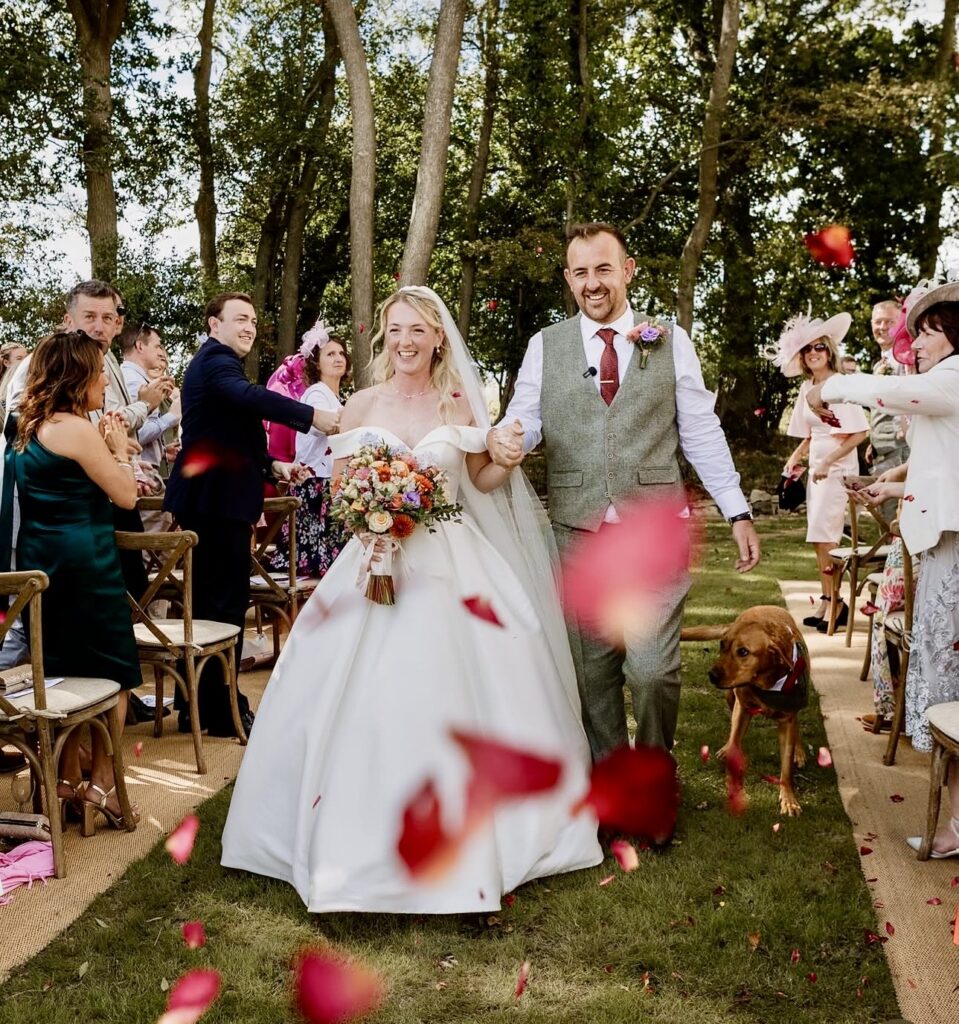 Bride laughing at family confetti during outdoor wedding ceremony