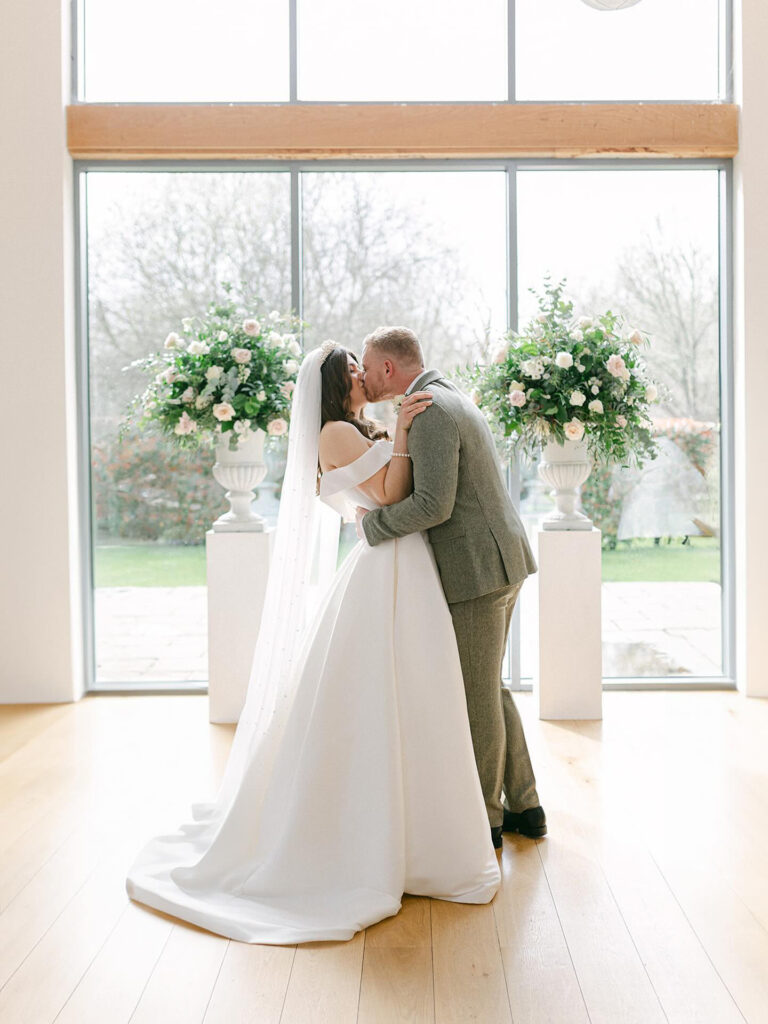 Bride and groom bridal portrait showcasing Stella York wedding dress alterations and elegant silhouette kissing at ceremony.