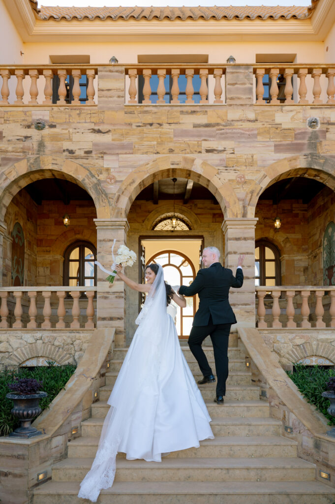 walking up the steps with groom hand in hand in a beautifully fitted dress