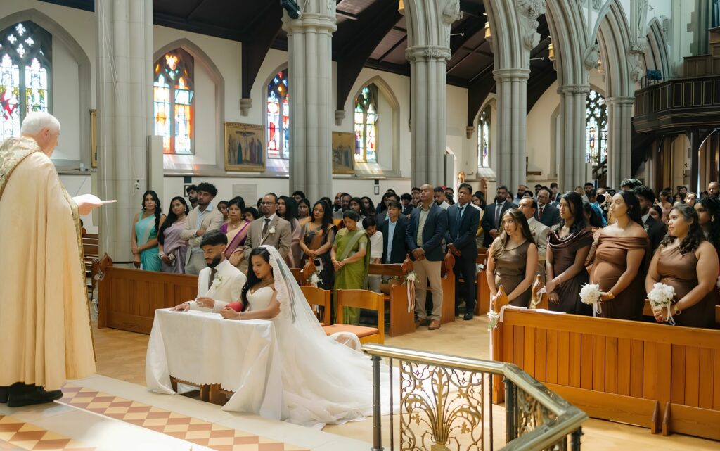 Bride wearing Allure Abella Carrington wedding dress after couture bridal alterations during church ceremony with groom.