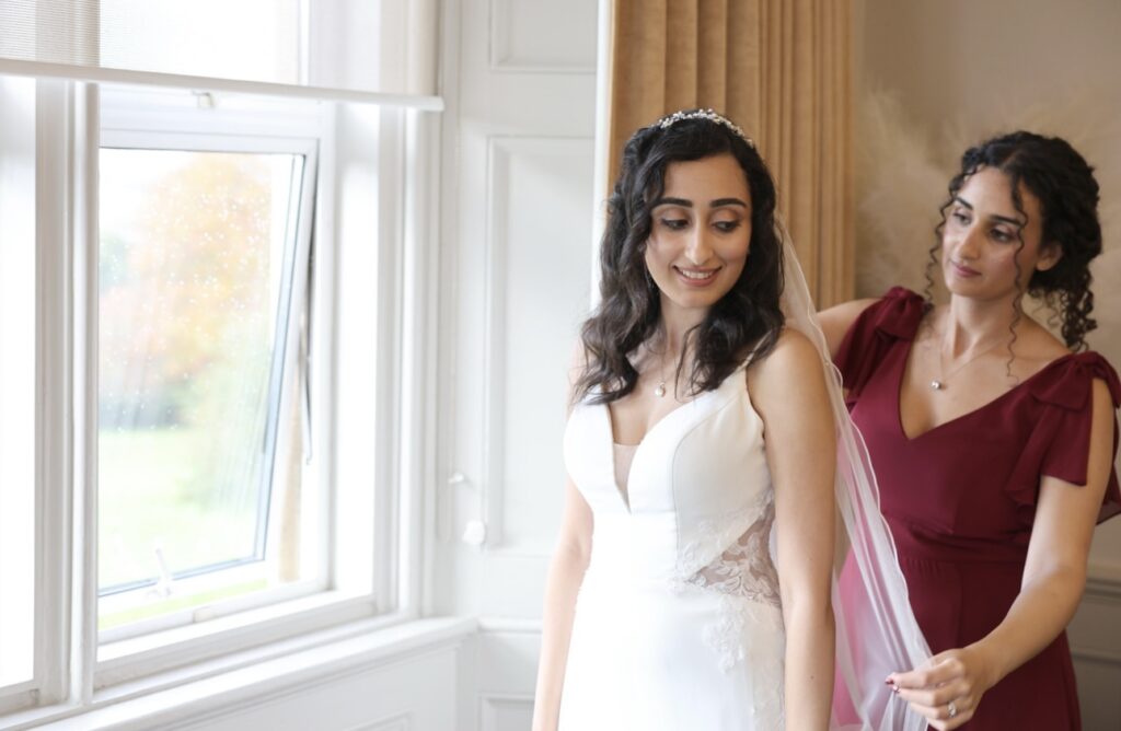 Bride having her veil adjusted before the wedding in her altered lace wedding dress