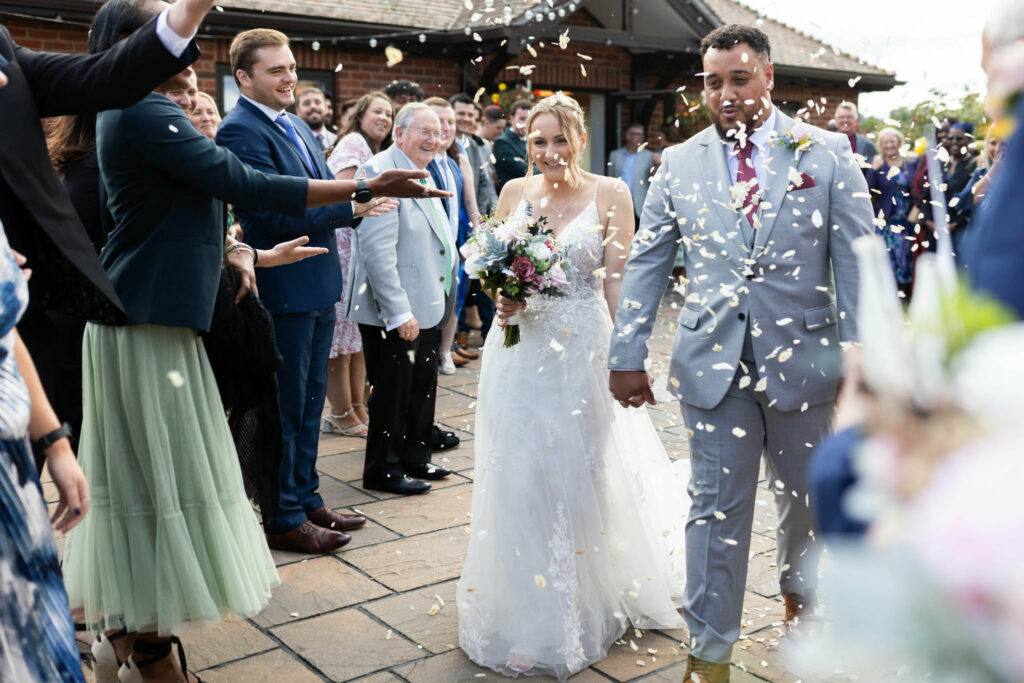 Newlyweds during confetti exit with the bride wearing her altered Essense of Australia wedding dress for a Kenley Bride.