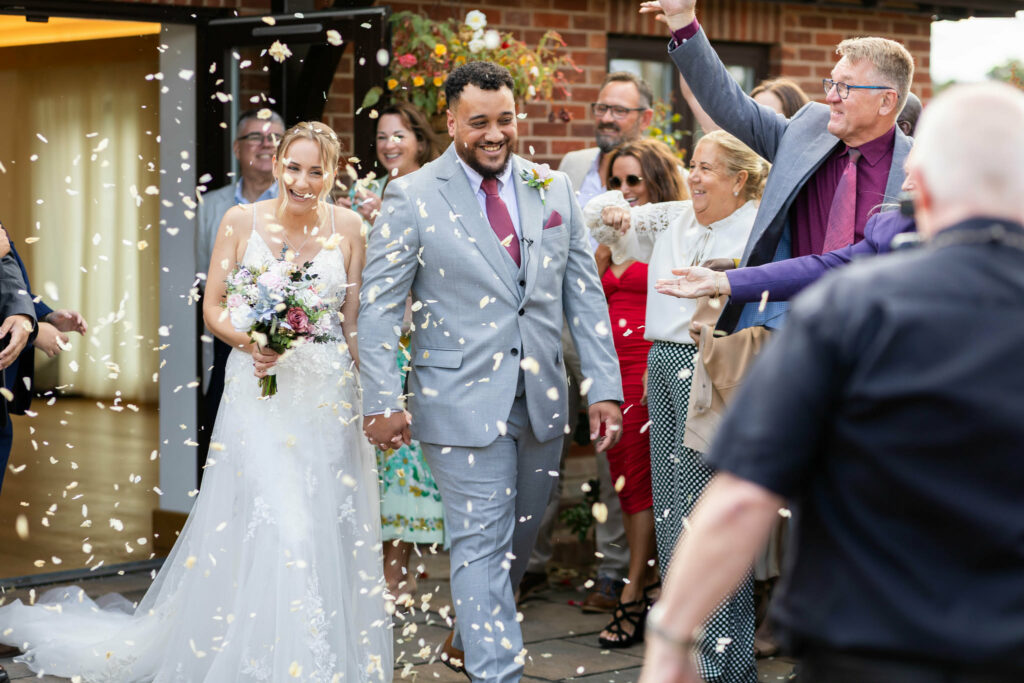 Newlyweds during confetti exit with the bride wearing her altered Essense of Australia wedding dress.