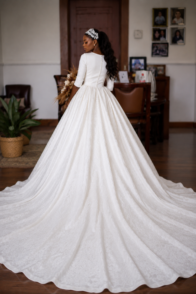 Back view of a Lagos bride showing the covered button detail and dramatic cathedral train of her satin wedding dress.