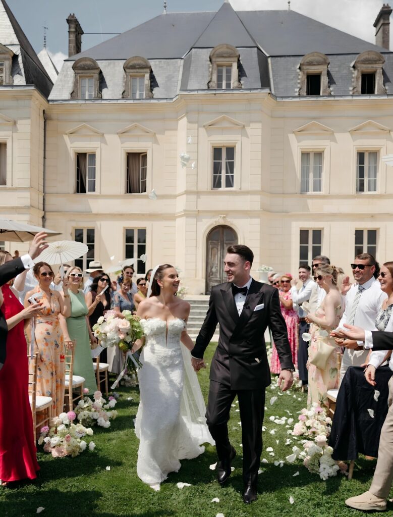 Bride and groom walking at Château Fengari wearing an expertly altered Ricca Sposa Como gown
