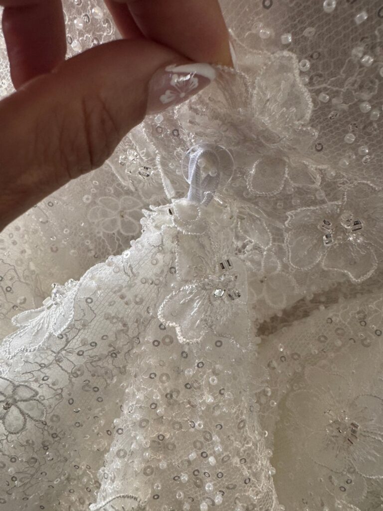 Hidden ribbon loop and button for a three point American bustle on a Ricca Sposa Como dress