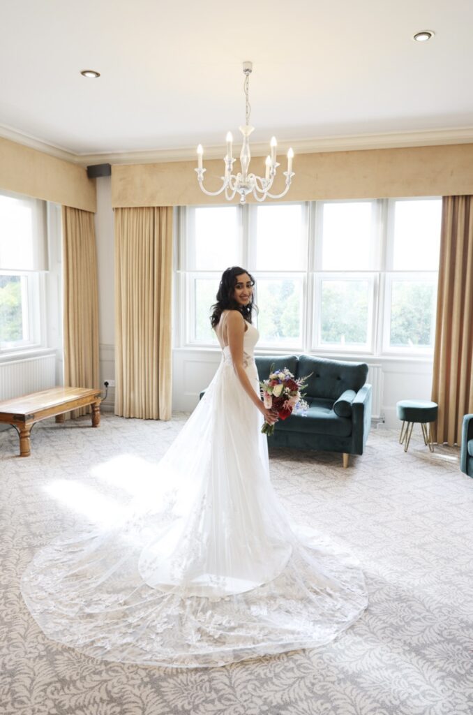 Full-length bridal portrait showing couture wedding dress size reduction and lace hem alterations