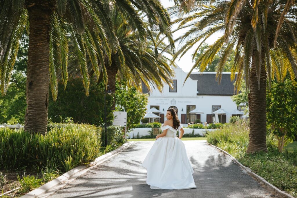 bustled up dress bride walking between trees.