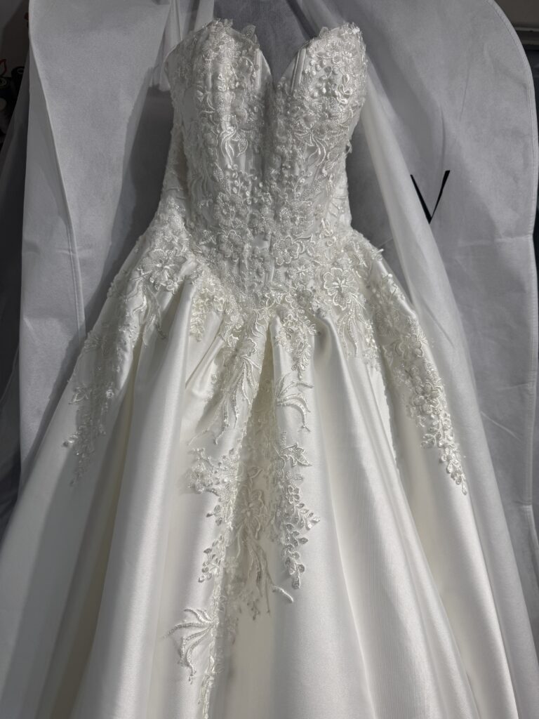 Bride showing the full Mikado skirt and lace-edged wedding dress train worn with cathedral veil.