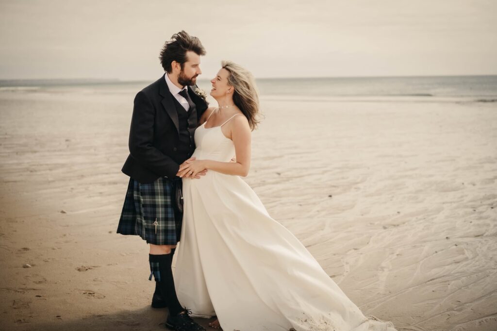 Bride and groom outside Pengersick Castle following their intimate Cornish wedding ceremony dress fitted to perfection.