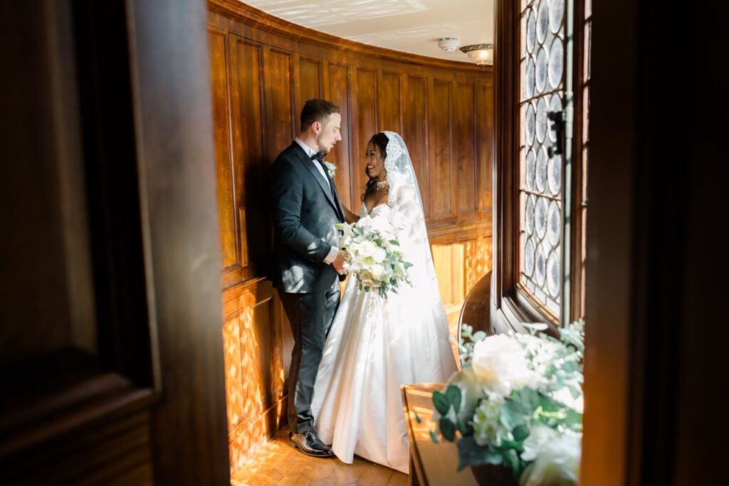 bride and groom standing near church window.