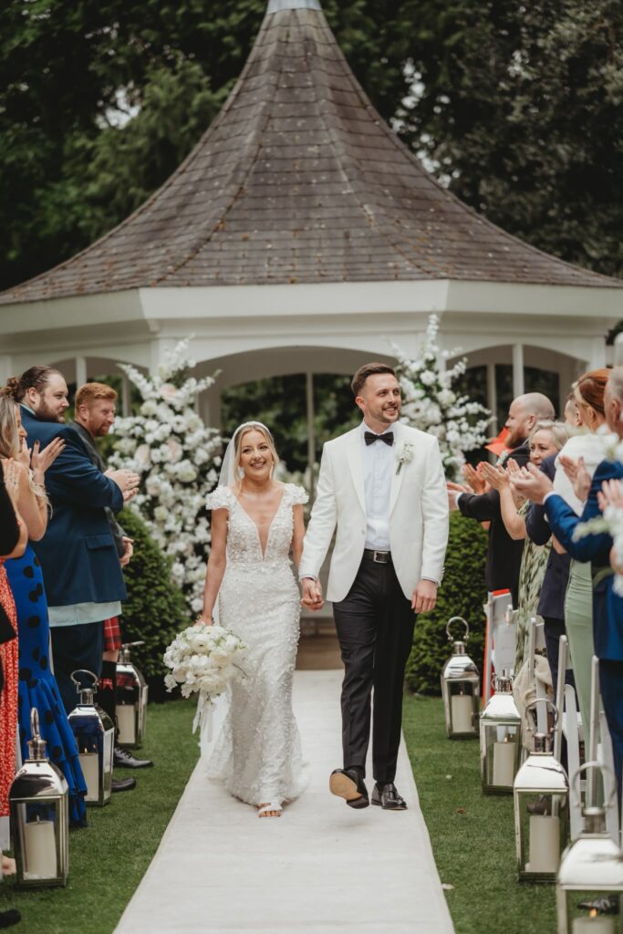 groom and bride ceremony together walking between guests.