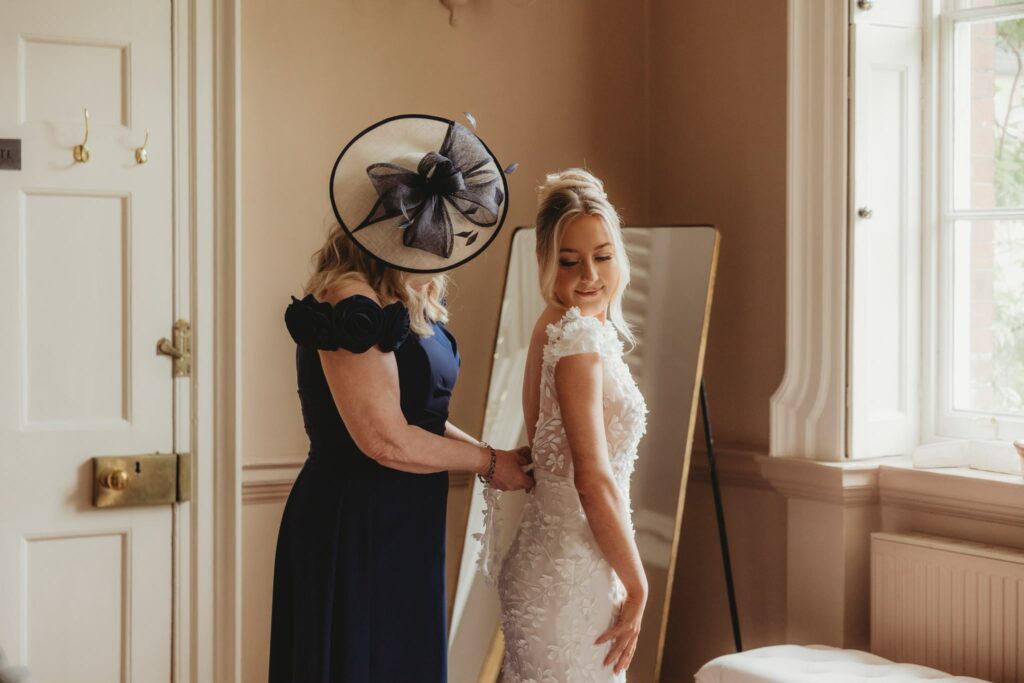 Made With Love Wedding dress alterations mum closing up brides dress getting ready.
