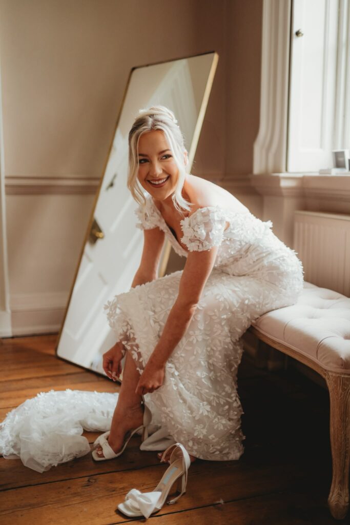 Intricate floral detailing on a Made With Love Darcy wedding dress bride putting on her shoes