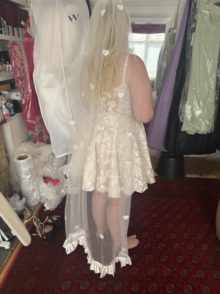 bride at her final fitting in a short Dama Couture Amanda lace wedding dress back view.
