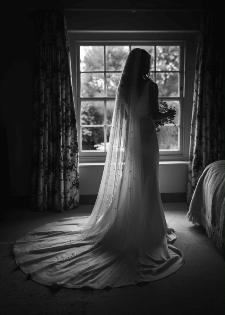 brides dress and cathedral veil looking stunning in black and white wedding photograph.