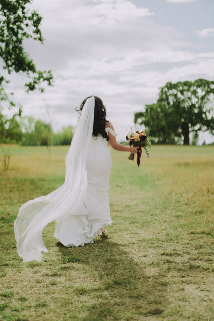 Bride running away back view showing the full gown in a natural wedding setting
