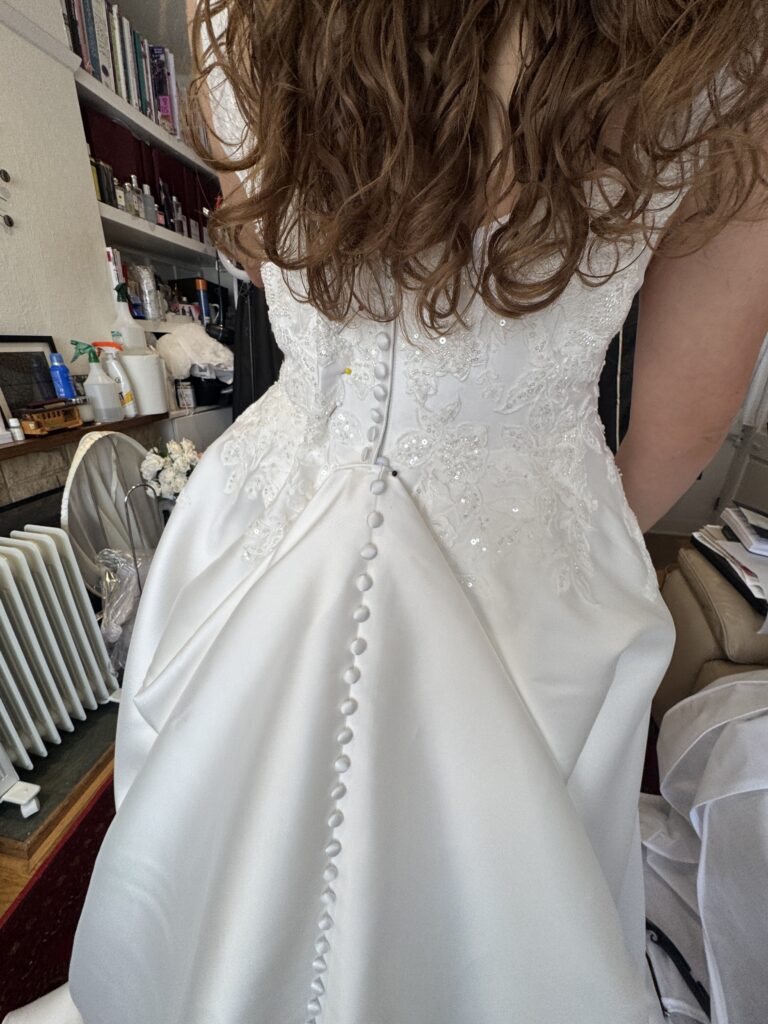 Taken in 5 cm via zip closure Stella York wedding dress alterations for a Bromley bride with the embroidered train pinned up in single american bustle point.