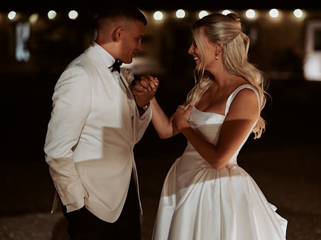 Bride and groom dancing together, showing the Ermana gown’s fitted bodice and pleated skirt