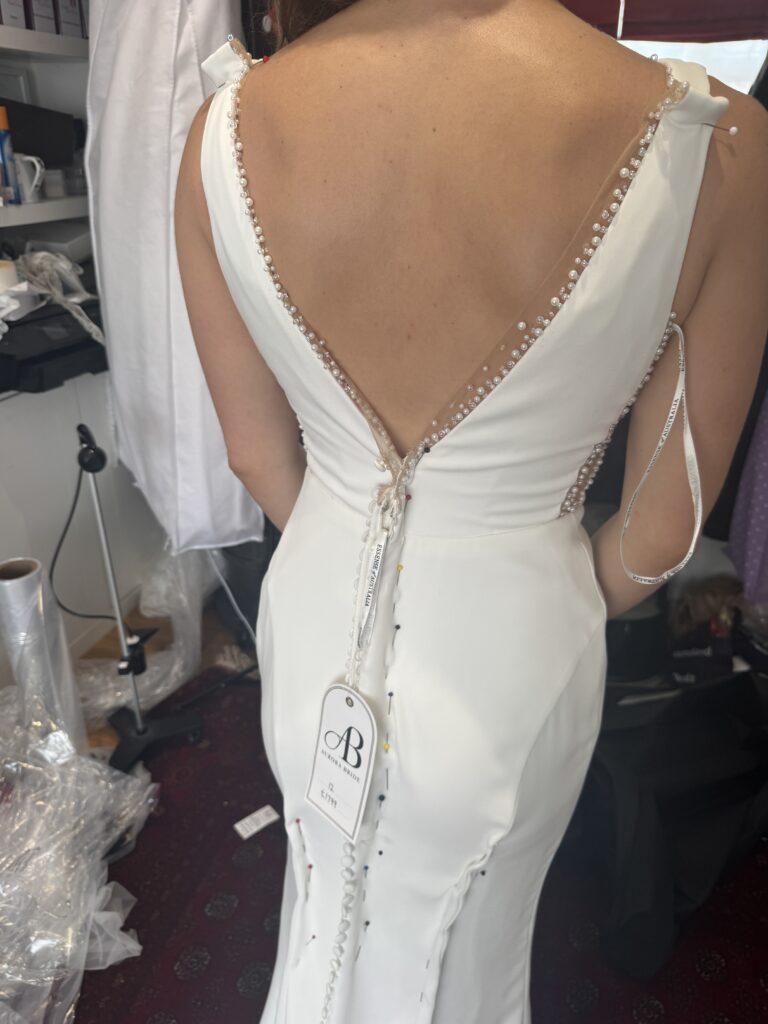Raynes Park Wedding Dress Alterations at first fitting showing dress oversized and pinned up all along centre back zip and from hip to below knees.