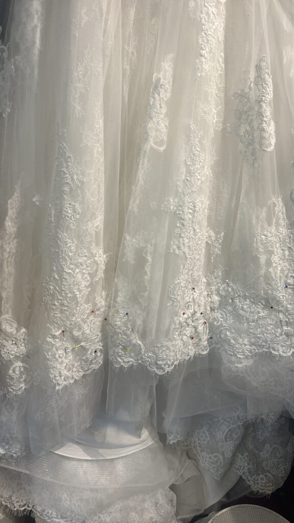 Sutton bride trying on her Anna Sorrano Mercia wedding dress at WED2B before alterations hem pinned
