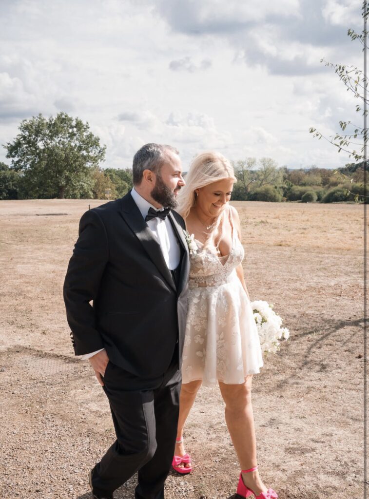 Bride and groom walking with the bride wearing her Dama Couture Amanda lace wedding dress
