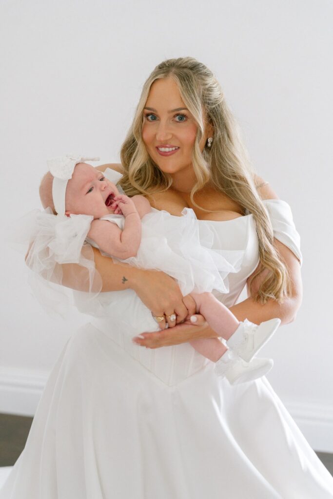 Isabella Grace Bridal Alterations for a Caterham bride holding her two month baby wearing bespoke pearl bow headband.