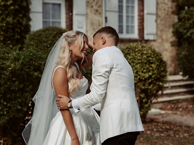 Bride and groom smiling together, with her veil falling over the full Mikado skirt
