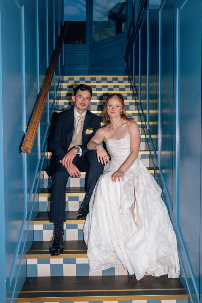 blue staircase photograph showing bride and groom happily sitting together.