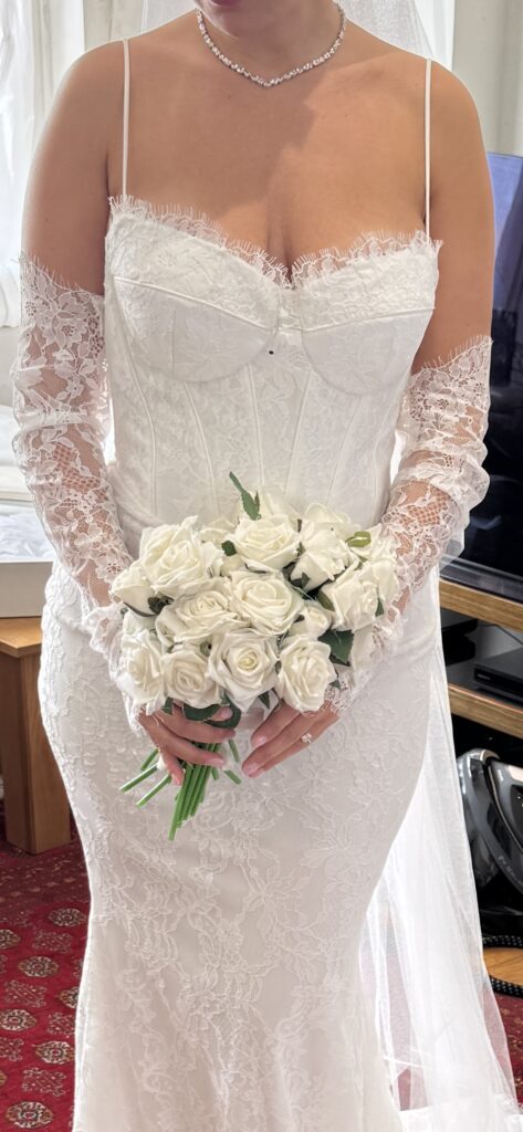 Bride wearing the WONA Concept Bronx lace wedding dress during alterations, showing the structured corset bodice close up, sweetheart neckline and fitted sleeves silhouette, Cobham Bridal Alterations.