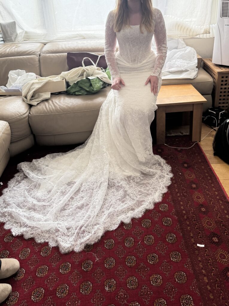 Bride seated in altered Maggie Sottero Ariadne wedding dress displaying the intricate lace train