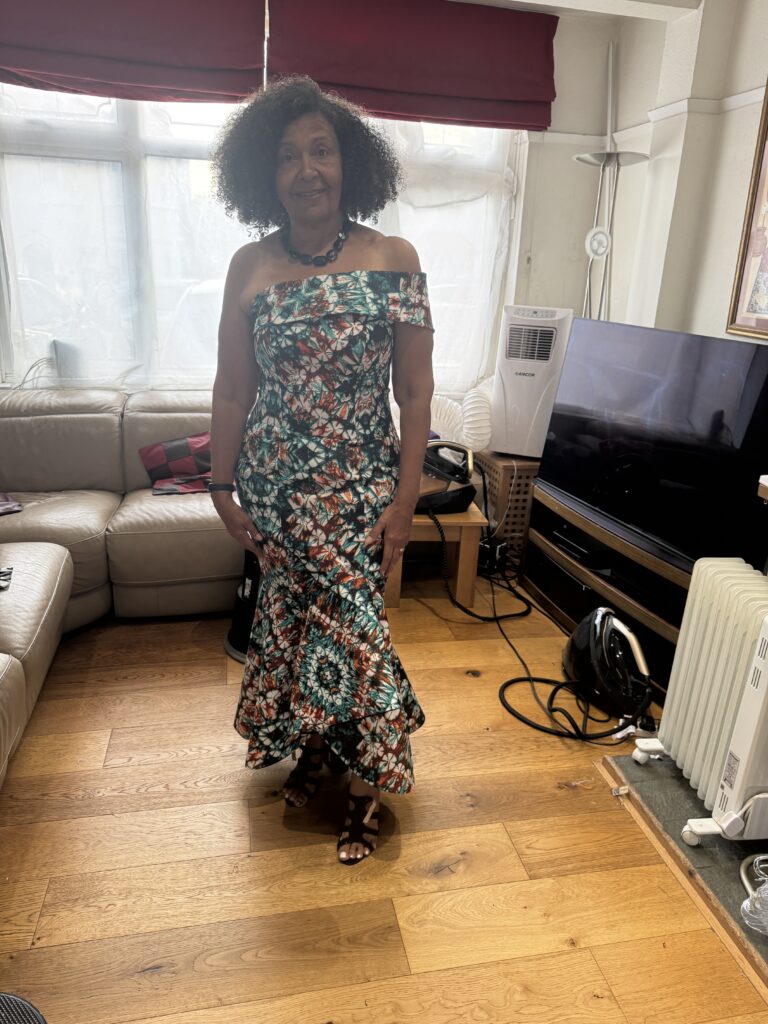 Mother of the bride modelling her finished bespoke teal and rust wax-print dress made from scratch with pattern drafting to final fitting at my Sutton Studio.