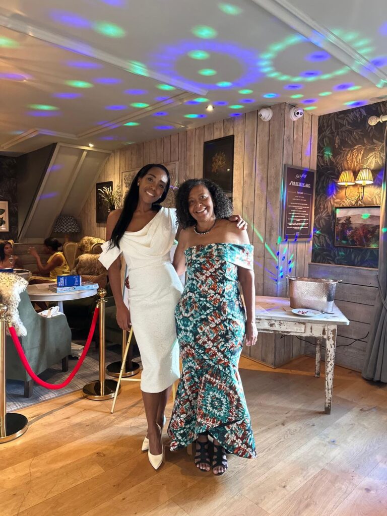 Client wearing her bespoke asymmetric wax-print dress alongside her daughter at the engagement celebration