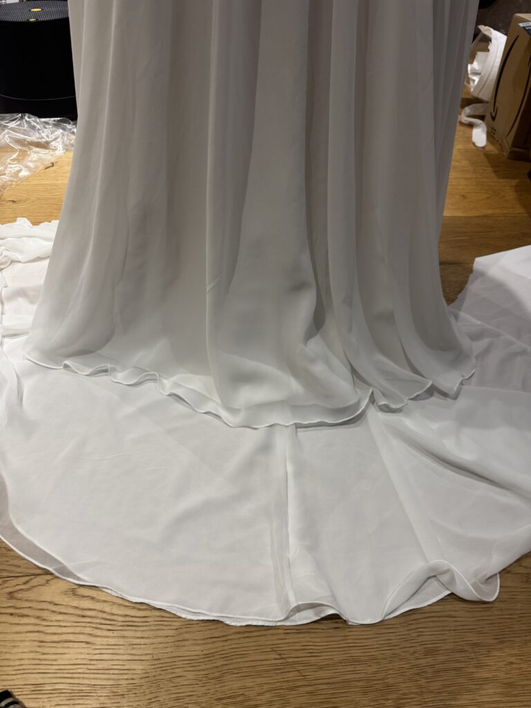 Close-up of the Marisol chiffon hem with excess fabric spread beneath the skirt during alterations