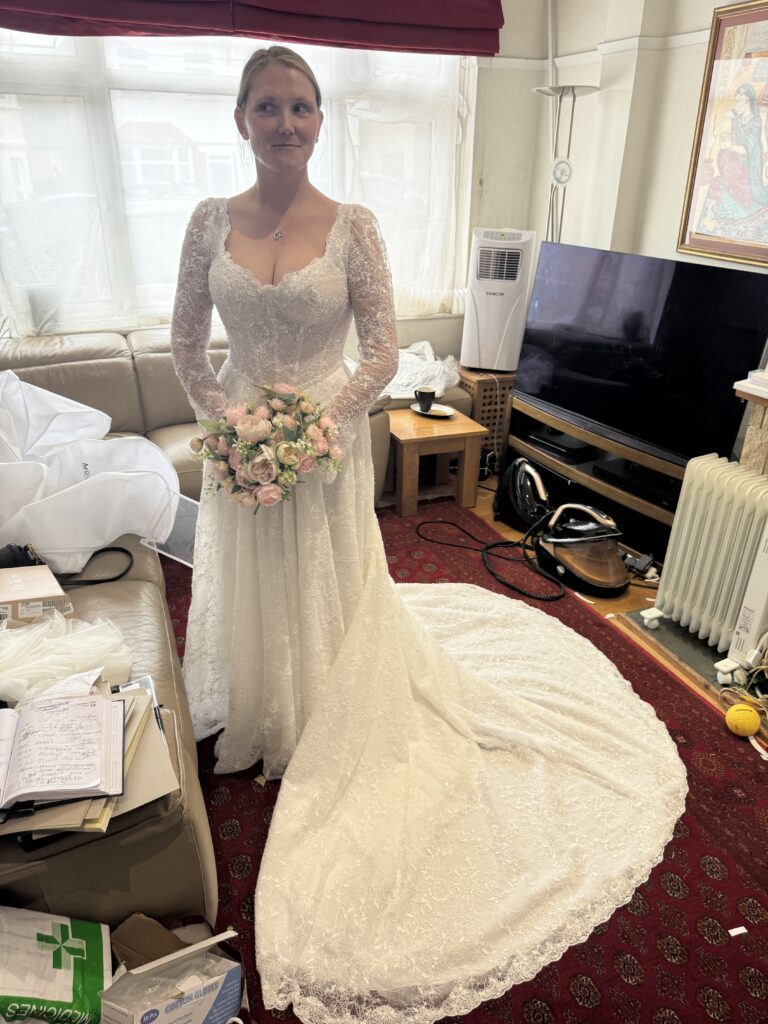 Banstead bride during Yedyna Estia wedding dress fitting with long embellished lace train and bouquet.