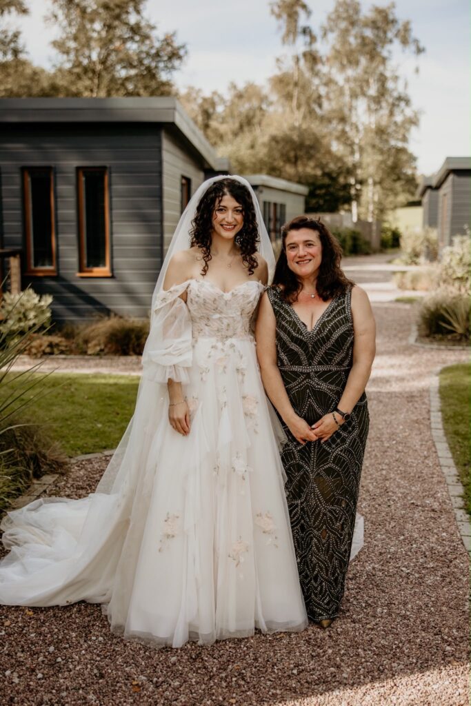 Mia in her altered Morilee bridal gown beside her mother wearing an embellished evening dress
